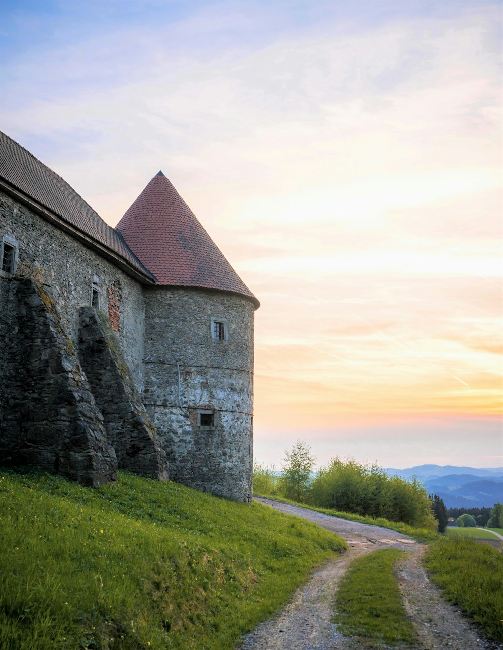 a stone building sitting on top of a lush green hillside