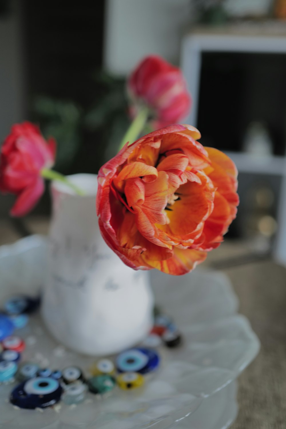 a white vase filled with red flowers on top of a table