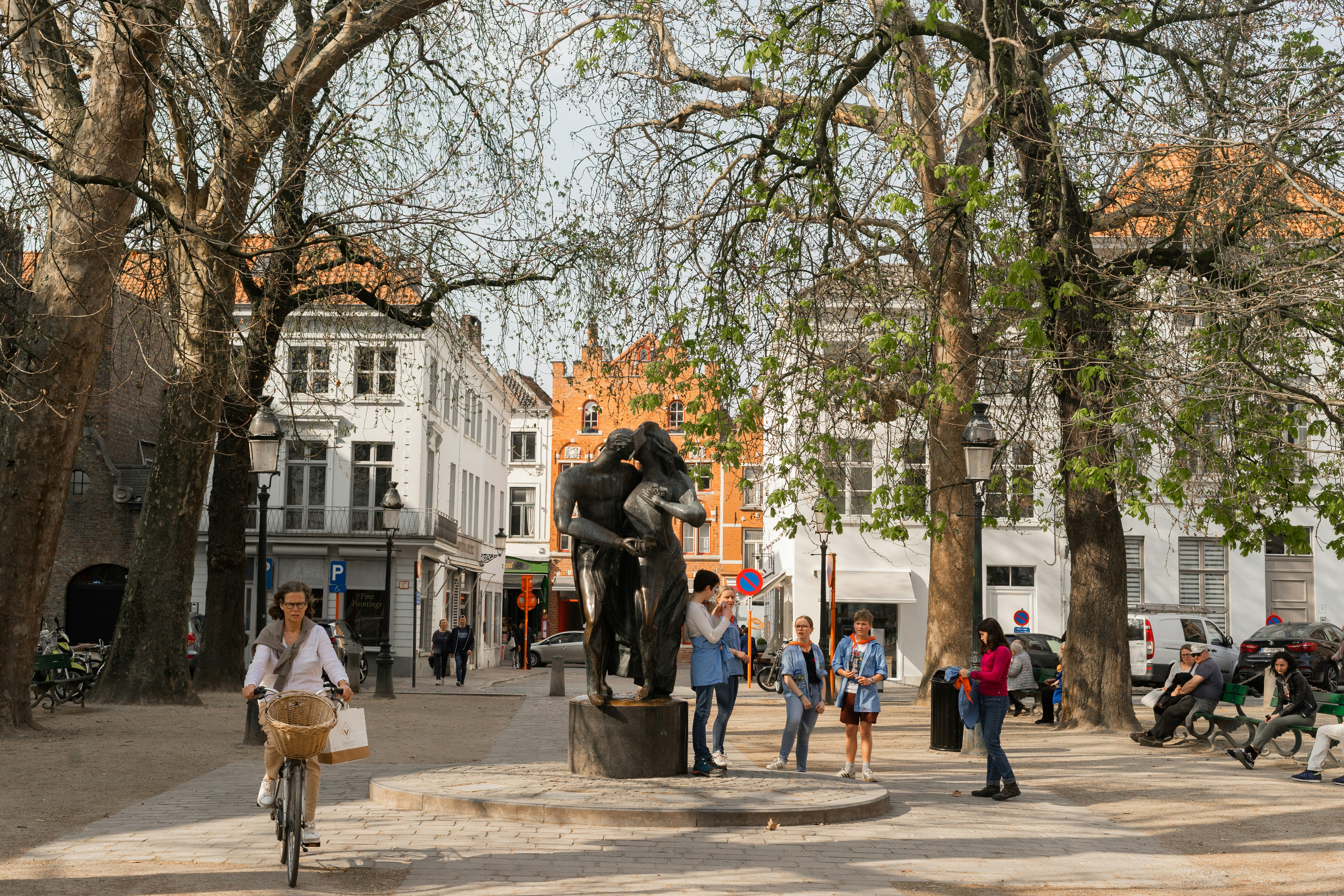 a group of people standing around a statue, 