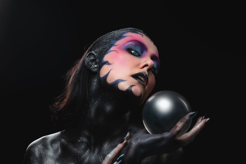 Una mujer con maquillaje negro sosteniendo una pelota