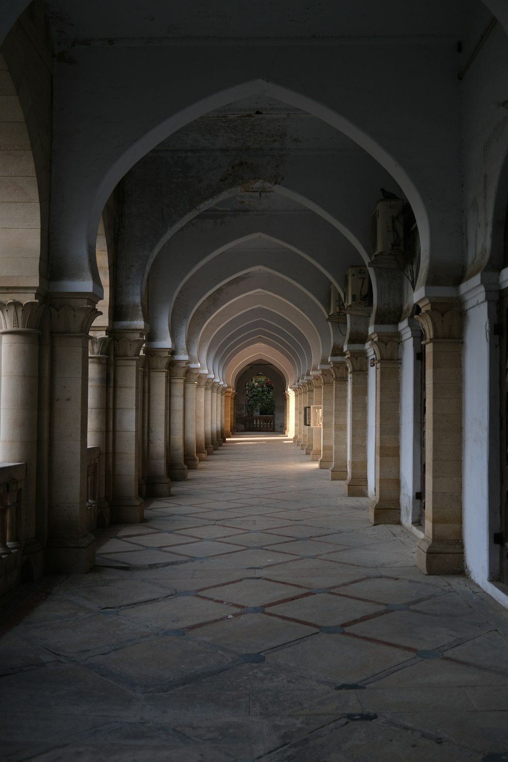 a long hallway with arches and a clock on the wall