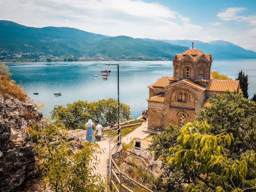 a group of people walking up a hill next to a body of water