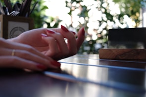 Vibrant red nails with a subtle matte finish displayed on a wooden table.