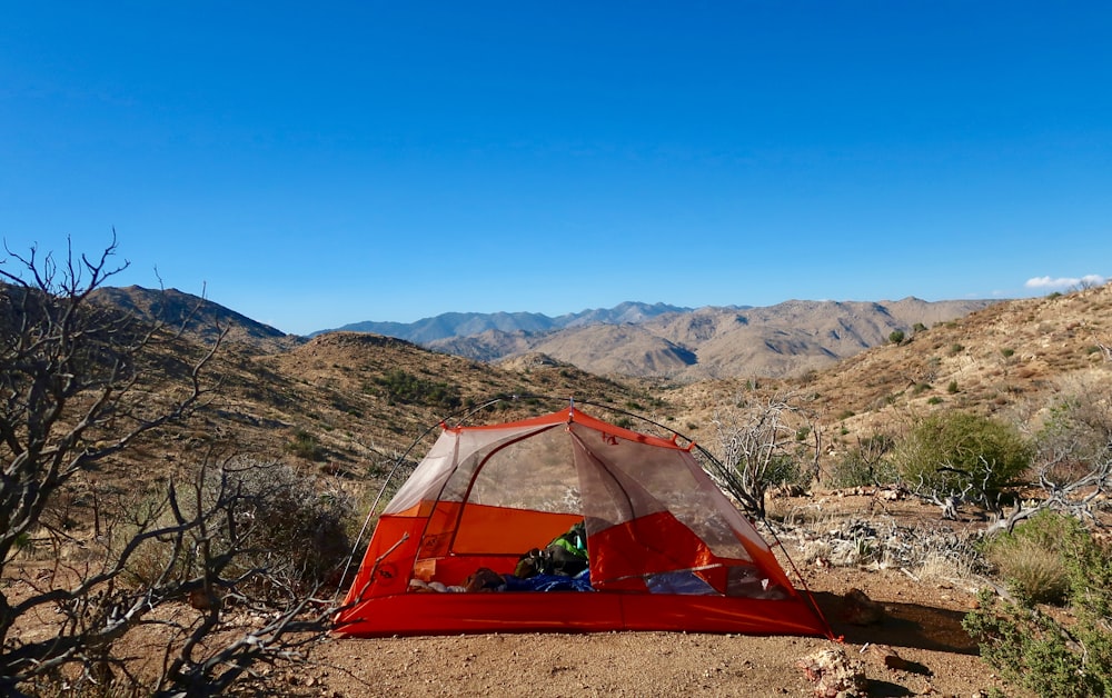 a tent pitched up in the desert with mountains in the background