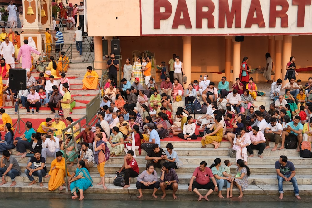 a group of people sitting on the side of a body of water