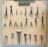 A pegboard is neatly organized with various tools, including scissors, pliers, hammers, and other hand tools. Each tool is secured on the board with a white strap. At the top, a label reads 'TOOLS OF THE TRADE'. The arrangement is symmetrical and orderly, with tools of different shapes and sizes.
