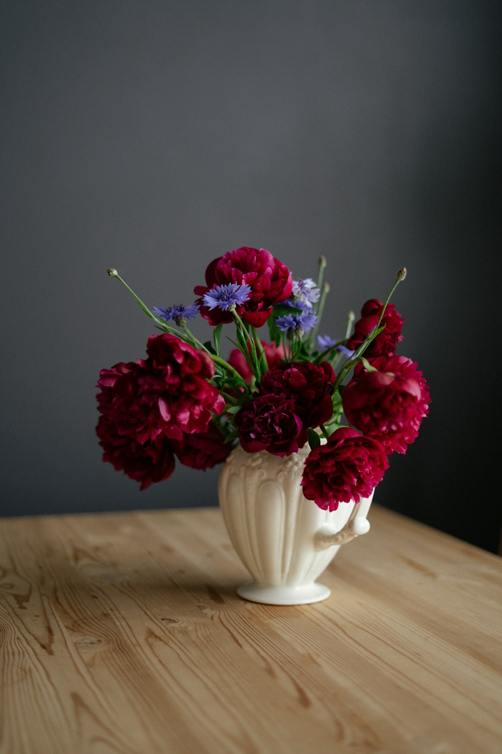 a white vase filled with red and purple flowers