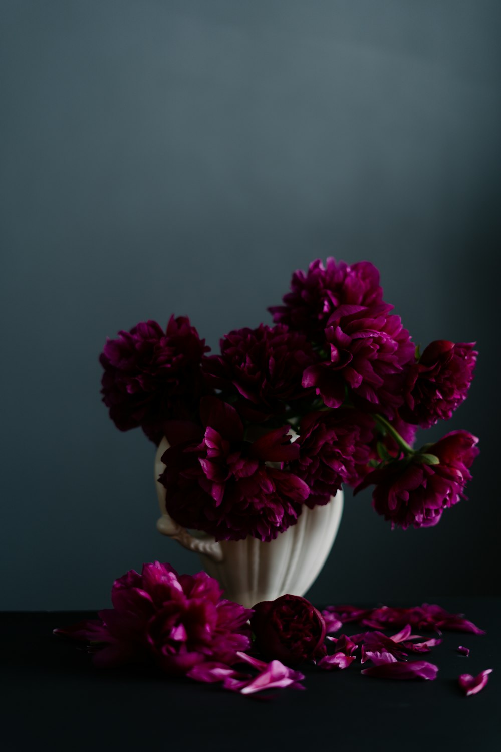 a white vase filled with purple flowers on top of a table