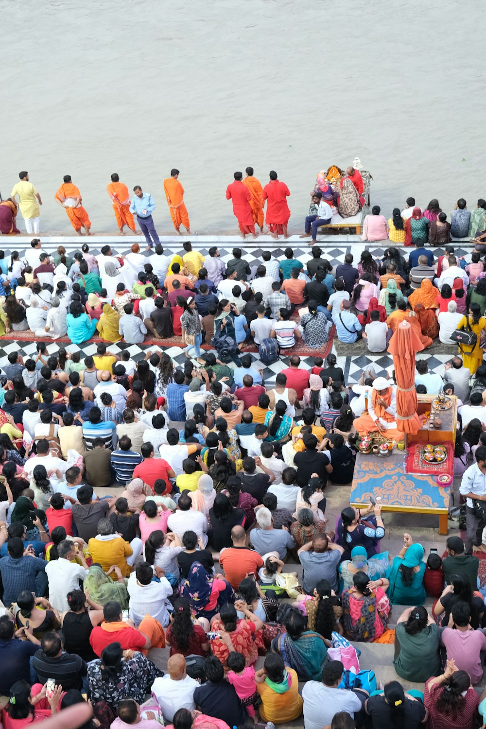 a large group of people standing around a body of water