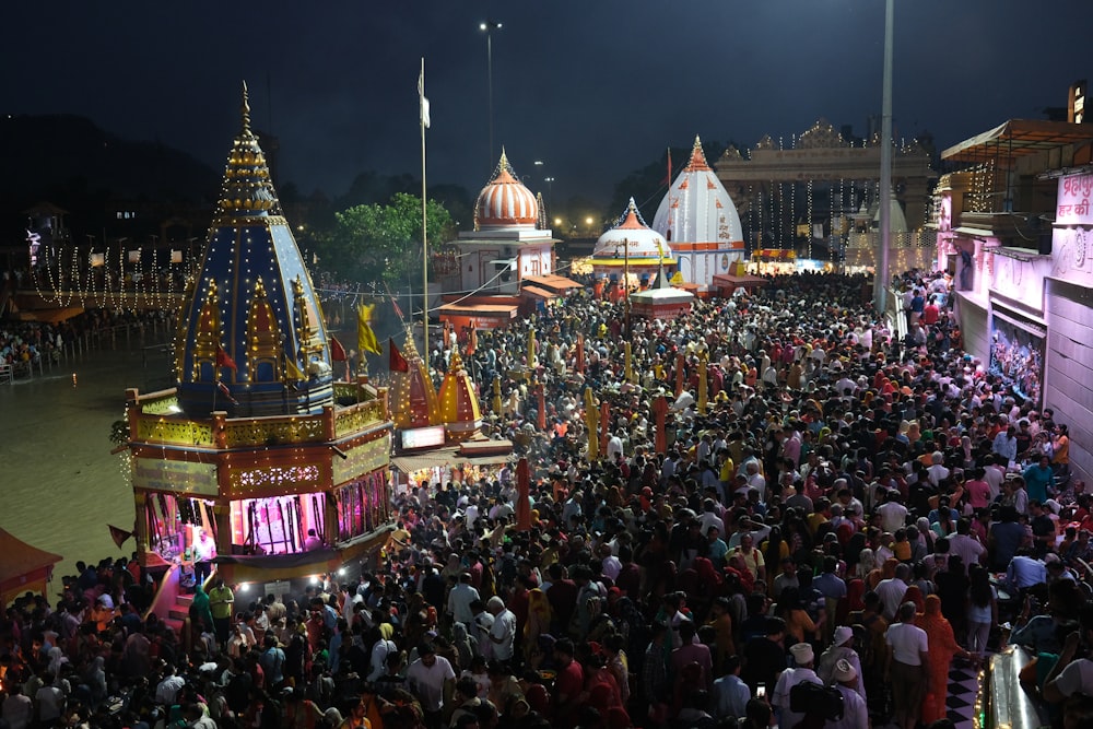 a crowd of people standing around a carnival at night