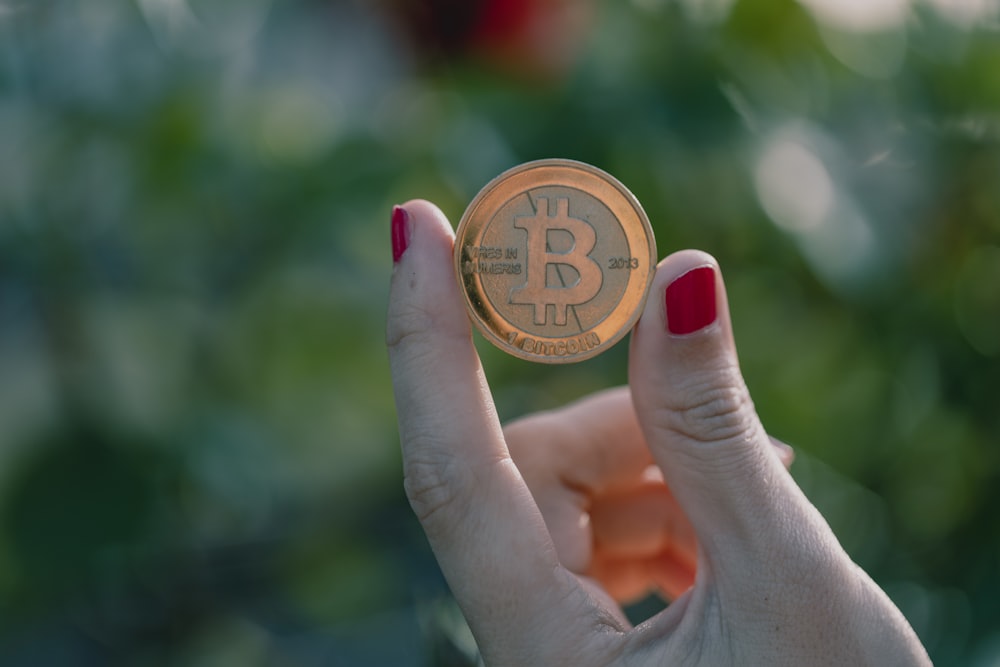 a woman holding a bit coin in her hand