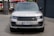 A silver Range Rover is parked on a concrete surface. The car is facing forward, displaying its grille and headlights prominently. The license plate on the front reads 'HH PR 500'. In the background, there are industrial elements, with a hint of a red and white vehicle partially visible.