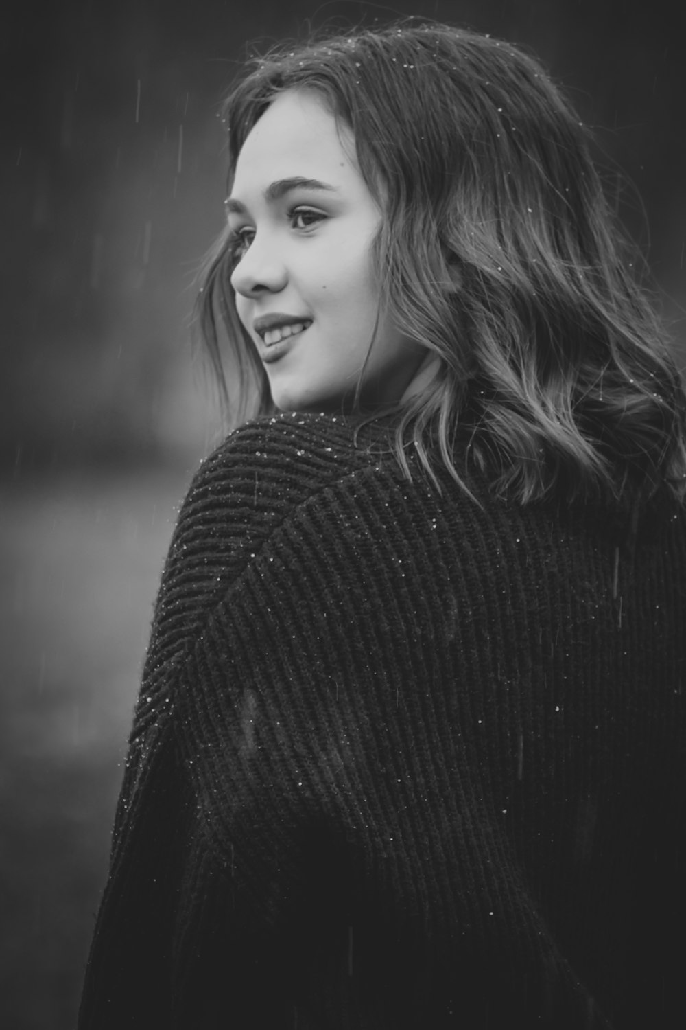 a black and white photo of a woman in the rain