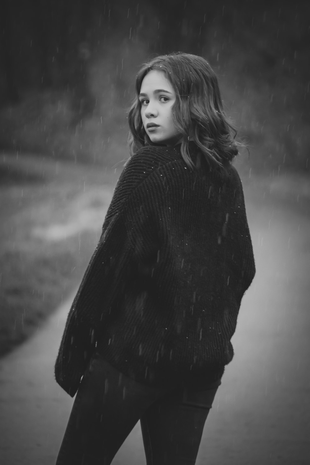 a woman standing in the rain wearing a black sweater