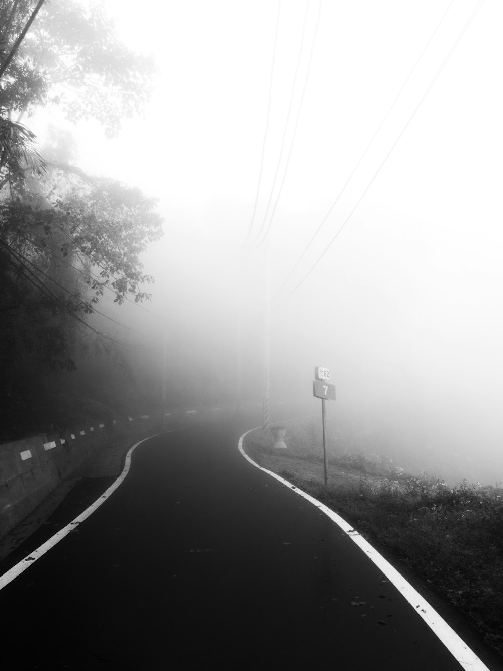 a foggy road with a street sign on the side of it