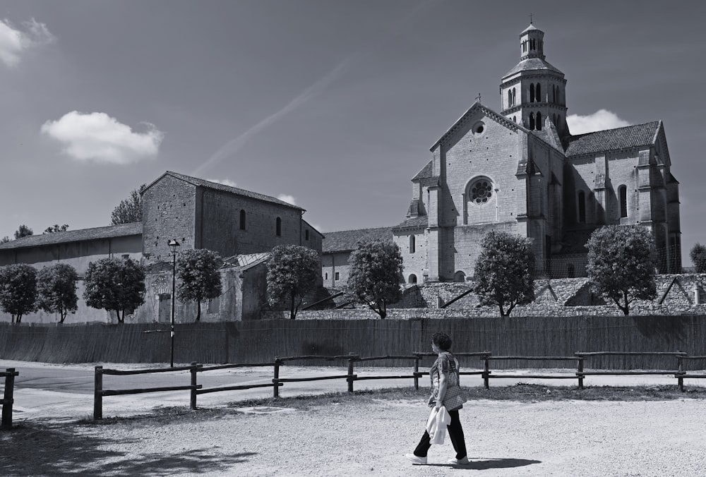 a black and white photo of a person walking in front of a church