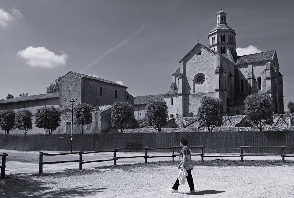 Una foto in bianco e nero di una persona che cammina davanti a una chiesa