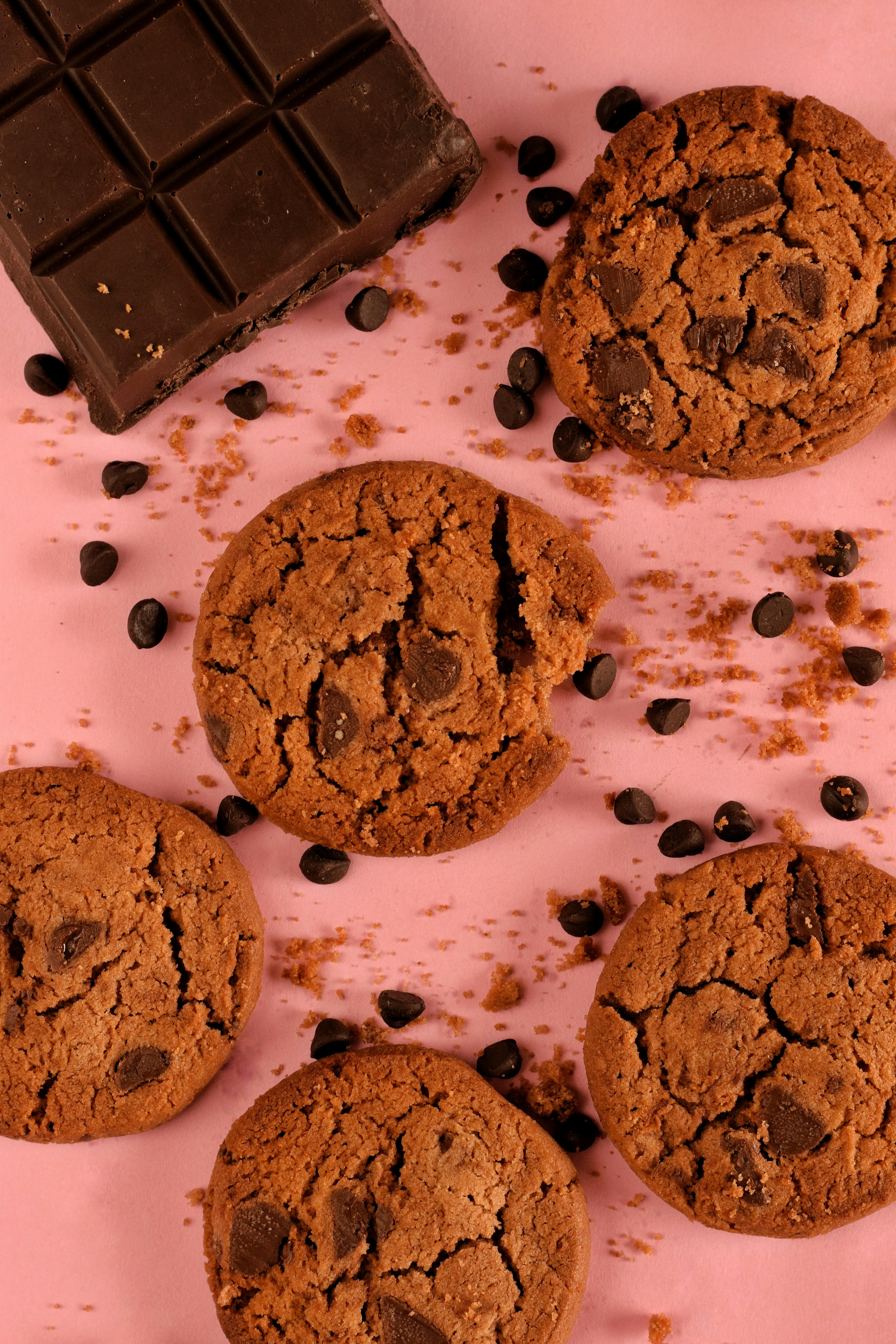chocolate chip cookies and a chocolate bar on a pink surface