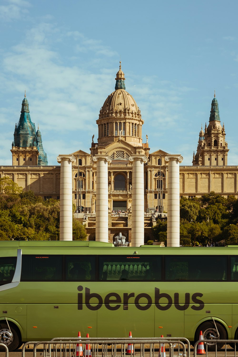 a green bus parked in front of a large building