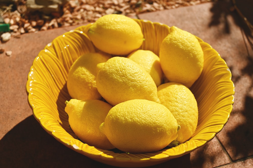 a yellow bowl filled with lemons on a table