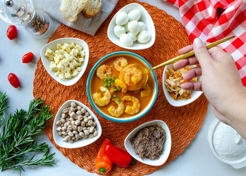 a person holding a spoon over a bowl of food