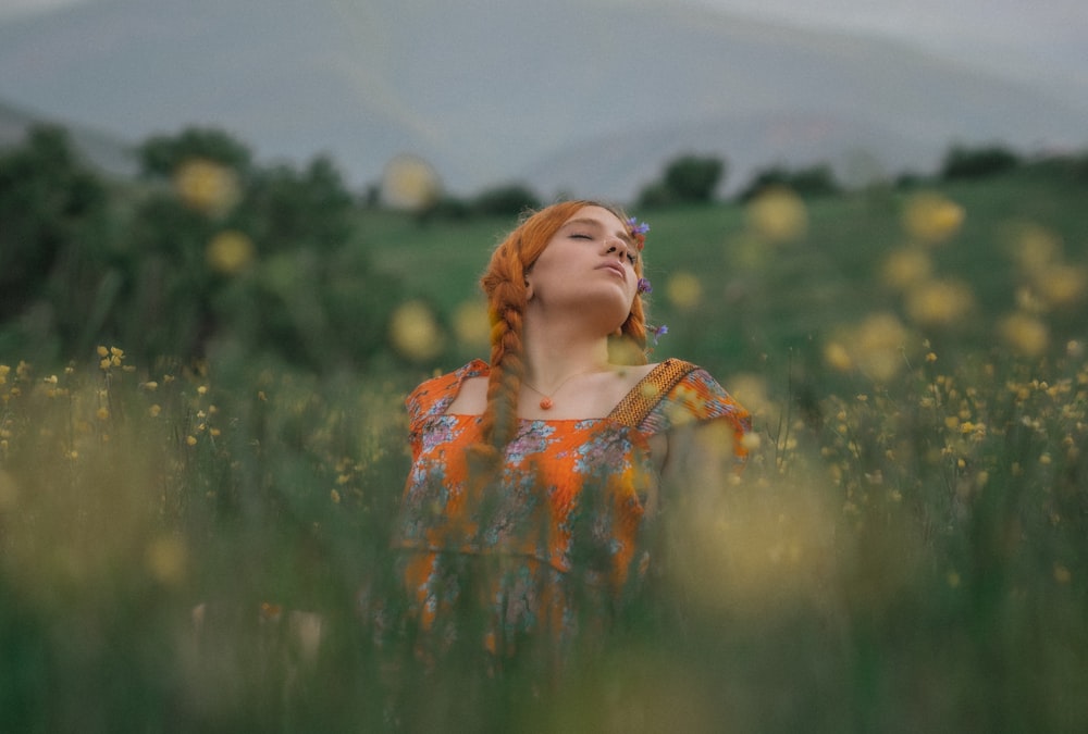 a woman standing in a field with her eyes closed