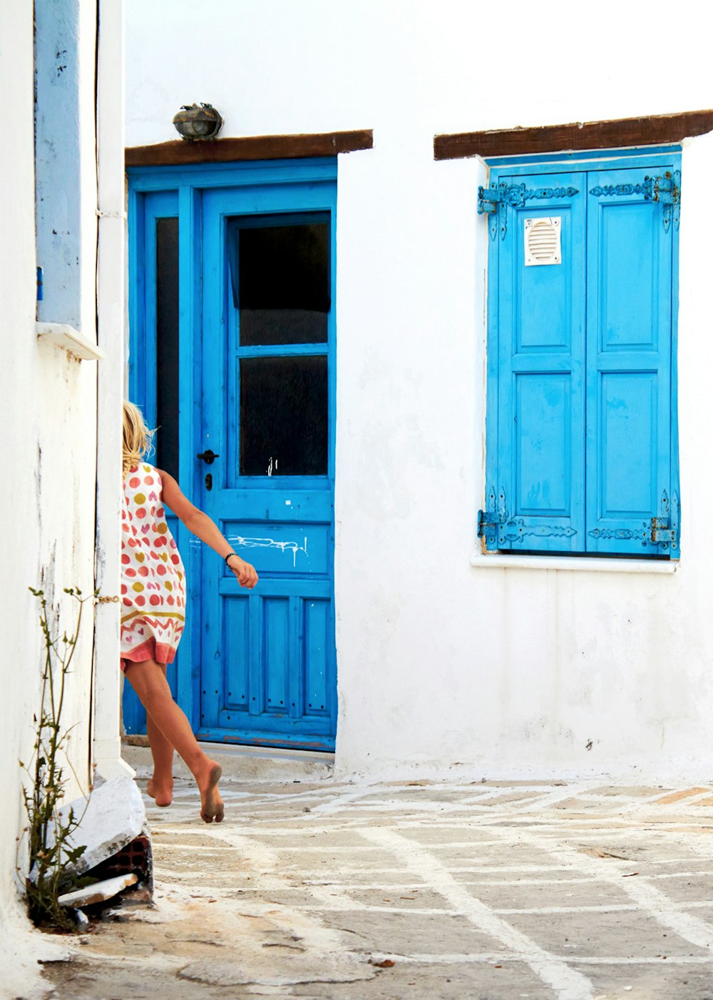 a woman in a red and white dress leaning against a blue door