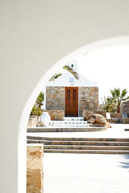 a white building with a brown door and steps