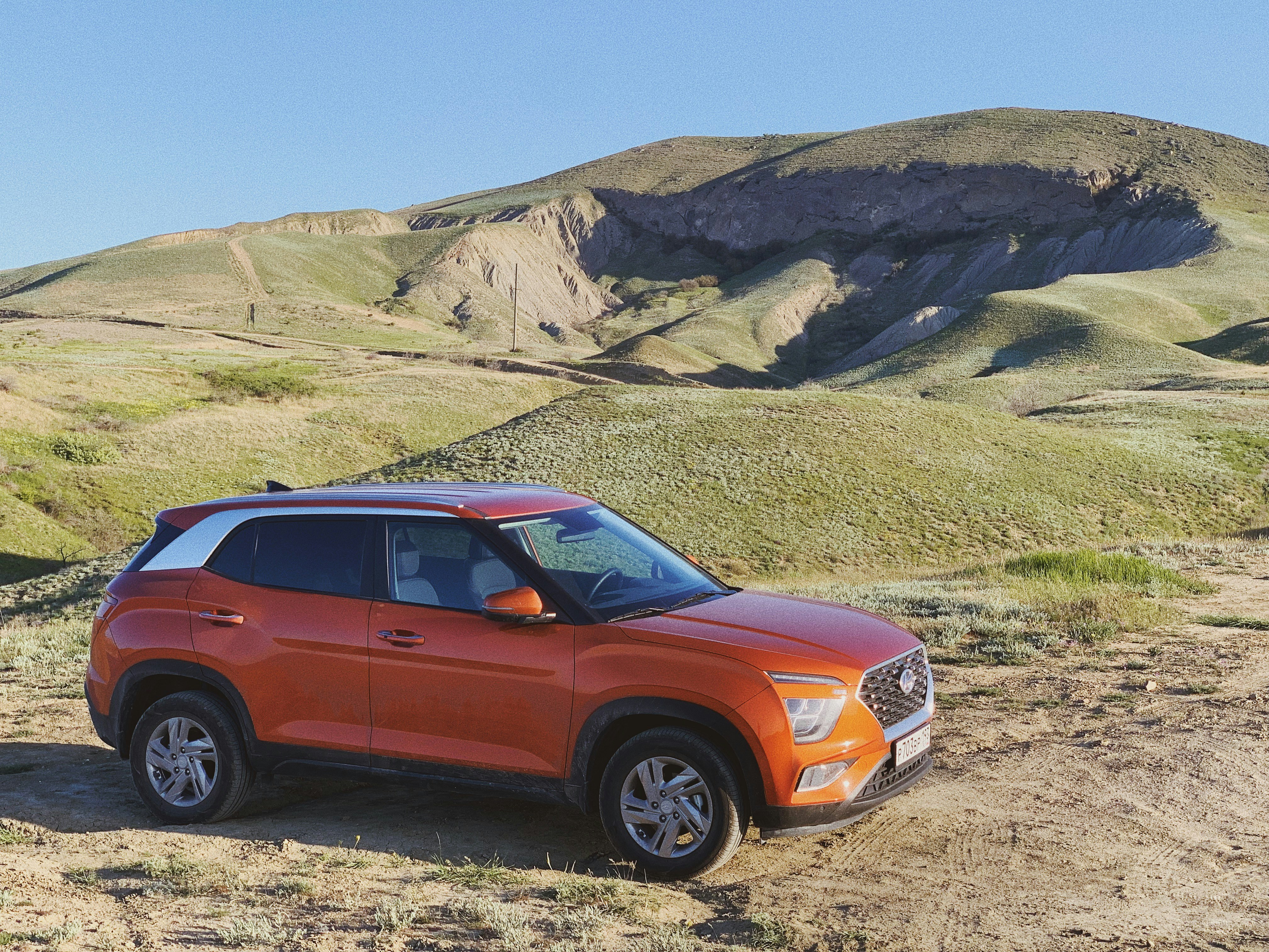 an orange suv parked on a dirt road
