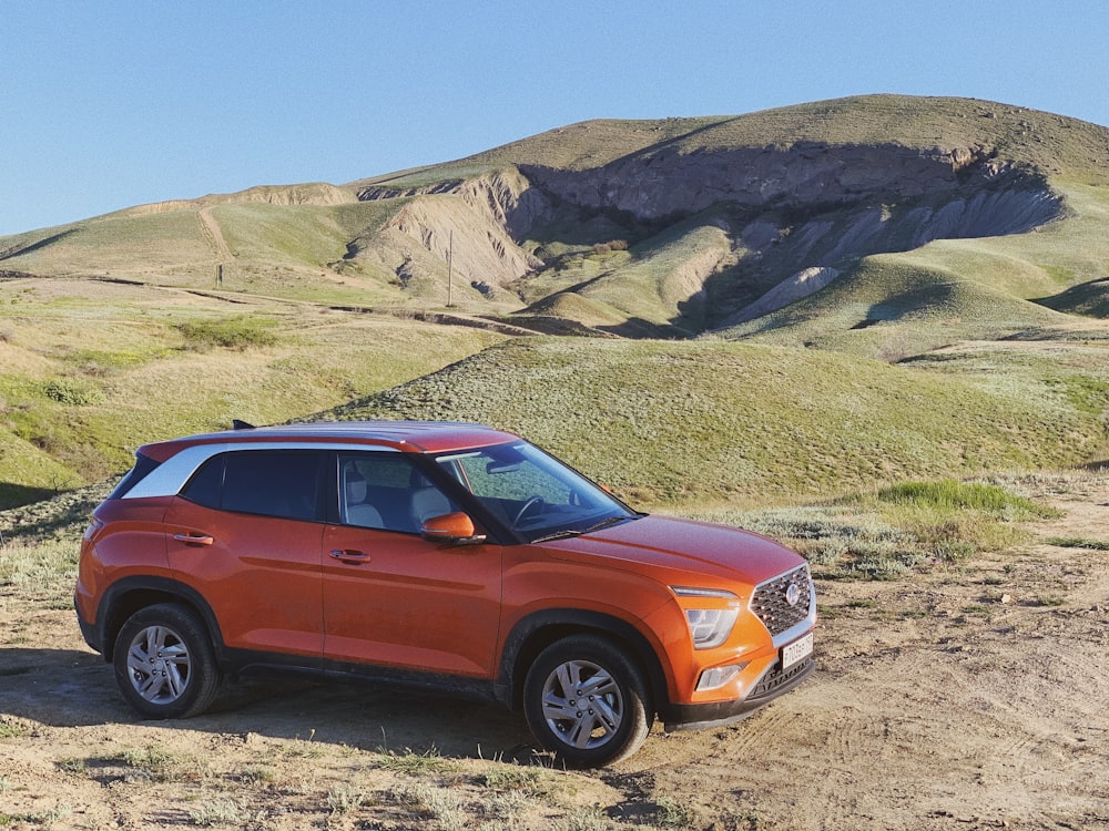 an orange suv parked on a dirt road