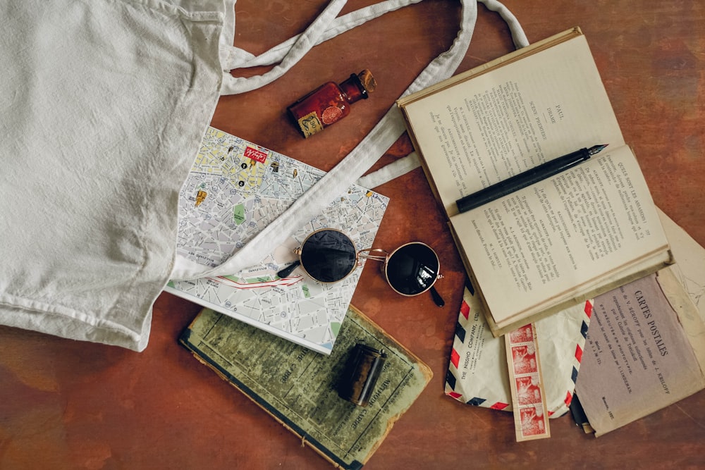 um livro aberto, um mapa, uma xícara de café e um par de