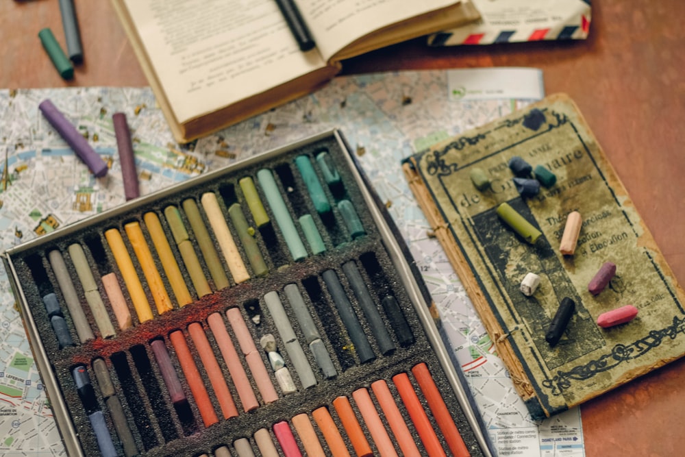 una caja de lápices de colores y un libro sobre una mesa