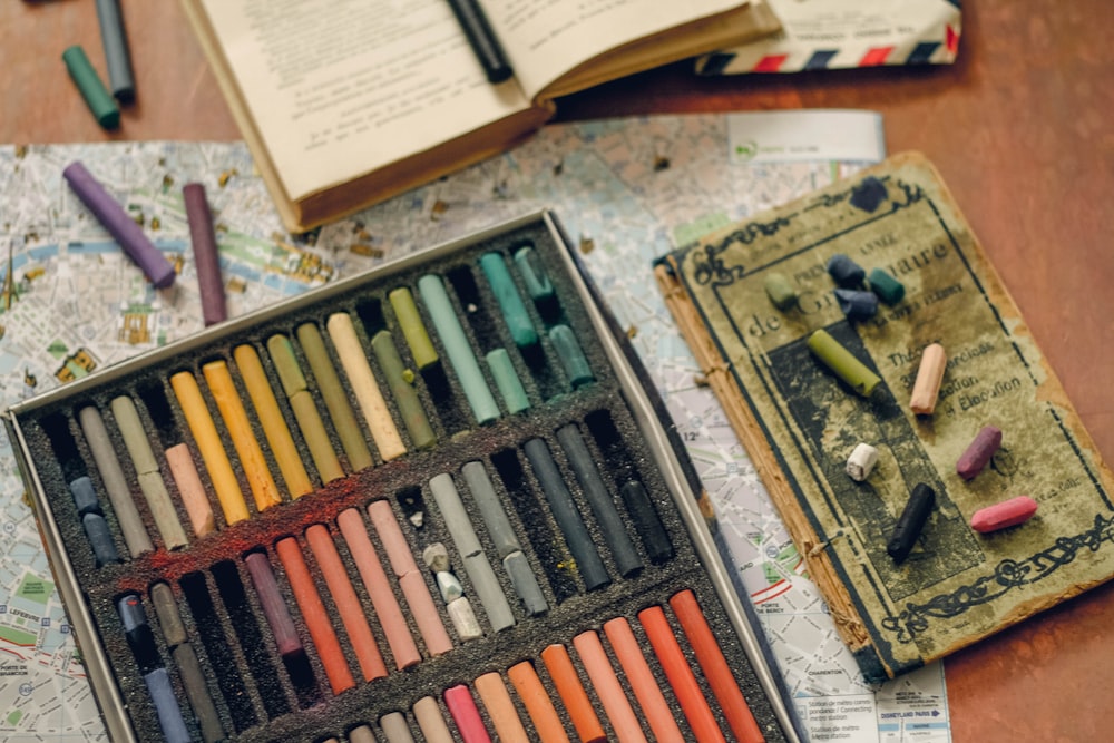 une boîte de crayons de couleur et un livre sur une table