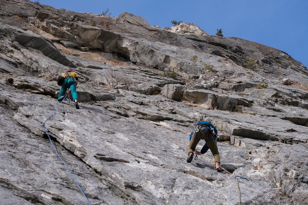 a couple of people climbing up a mountain