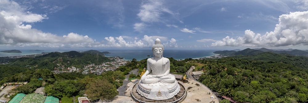 Eine große weiße Buddha-Statue auf einem üppigen grünen Hügel