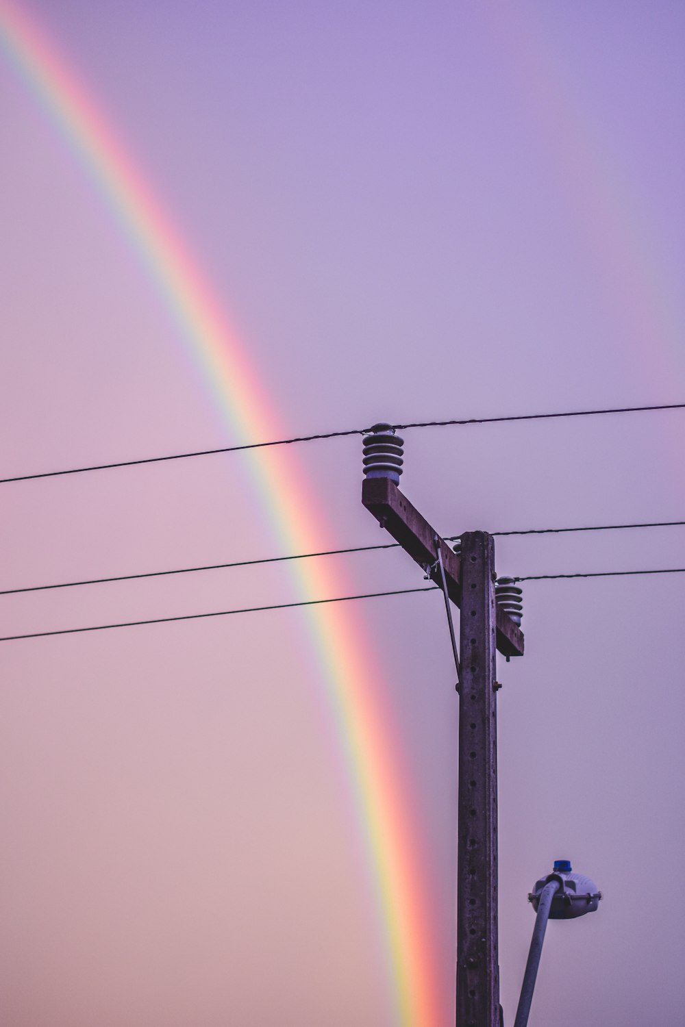 a double rainbow in the sky over power lines