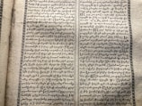 A vintage manuscript page containing two columns of handwritten text on aged paper. The script has a decorative border and is written in an ornate style that suggests historical or ancient content.