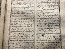 A vintage manuscript page containing two columns of handwritten text on aged paper. The script has a decorative border and is written in an ornate style that suggests historical or ancient content.