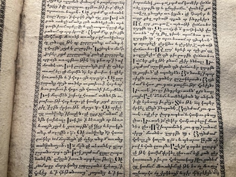 A vintage manuscript page containing two columns of handwritten text on aged paper. The script has a decorative border and is written in an ornate style that suggests historical or ancient content.