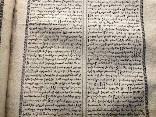 A vintage manuscript page containing two columns of handwritten text on aged paper. The script has a decorative border and is written in an ornate style that suggests historical or ancient content.