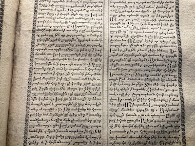 A vintage manuscript page containing two columns of handwritten text on aged paper. The script has a decorative border and is written in an ornate style that suggests historical or ancient content.