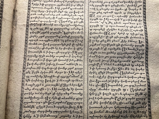A vintage manuscript page containing two columns of handwritten text on aged paper. The script has a decorative border and is written in an ornate style that suggests historical or ancient content.