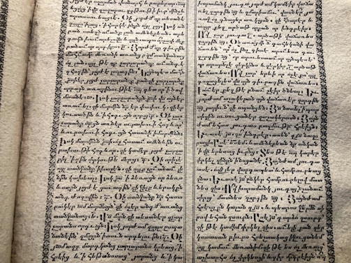 A vintage manuscript page containing two columns of handwritten text on aged paper. The script has a decorative border and is written in an ornate style that suggests historical or ancient content.
