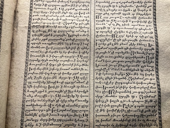 A vintage manuscript page containing two columns of handwritten text on aged paper. The script has a decorative border and is written in an ornate style that suggests historical or ancient content.