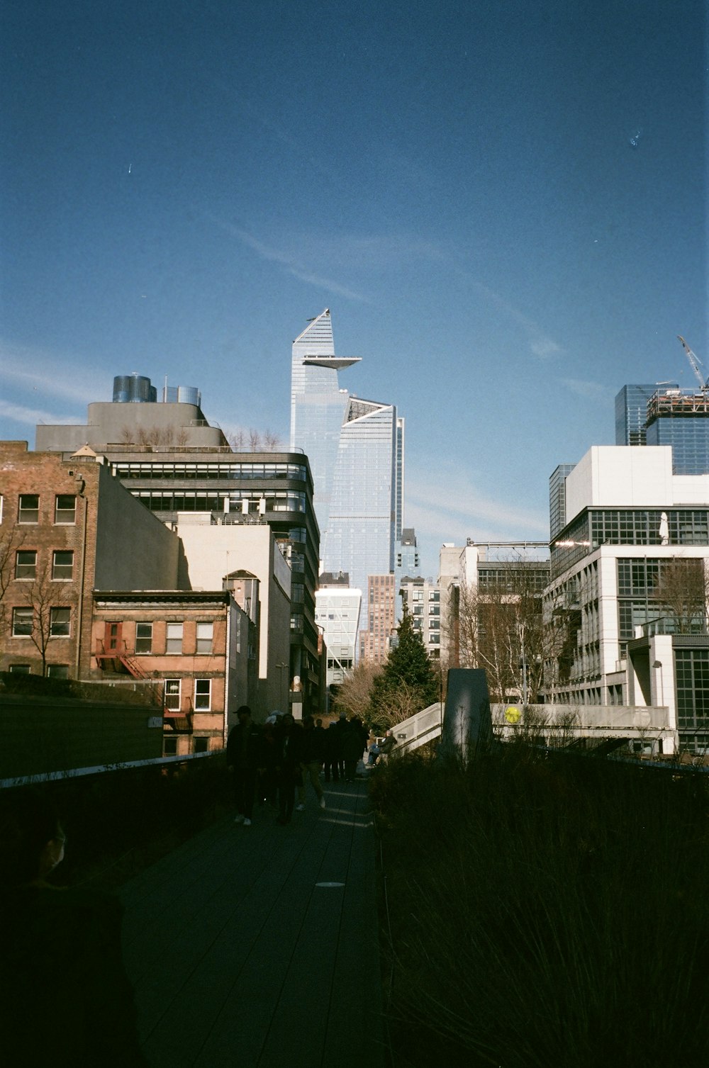 a group of people walking down a sidewalk next to tall buildings