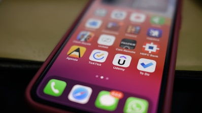 A close-up of a smartphone screen displaying a variety of applications, arranged in a grid pattern. The apps have distinct icons and include names like Agenda, TickTick, and Udemy. The background is blurred, highlighting the focus on the phone's display.