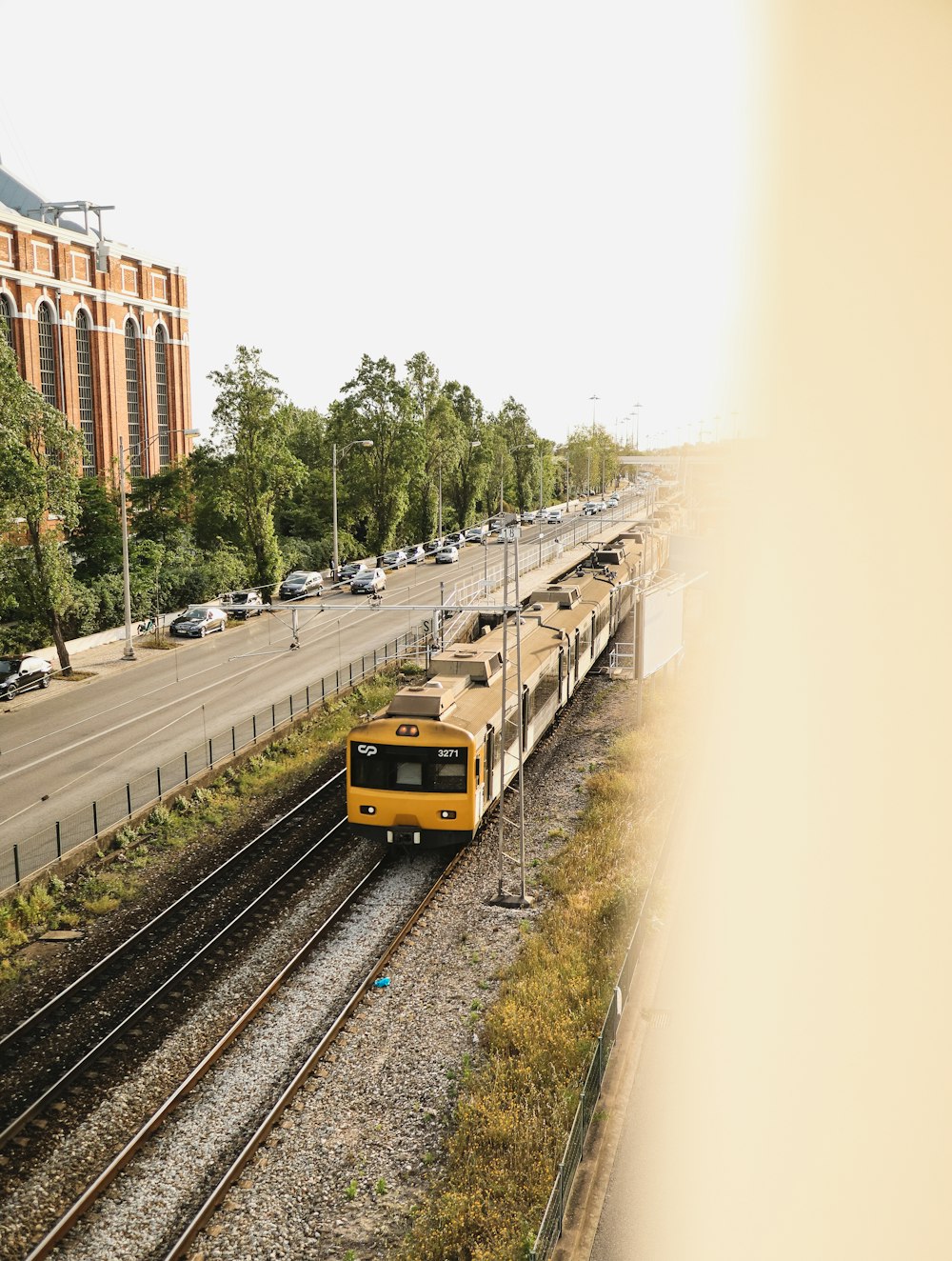 a yellow train traveling down train tracks next to a tall building