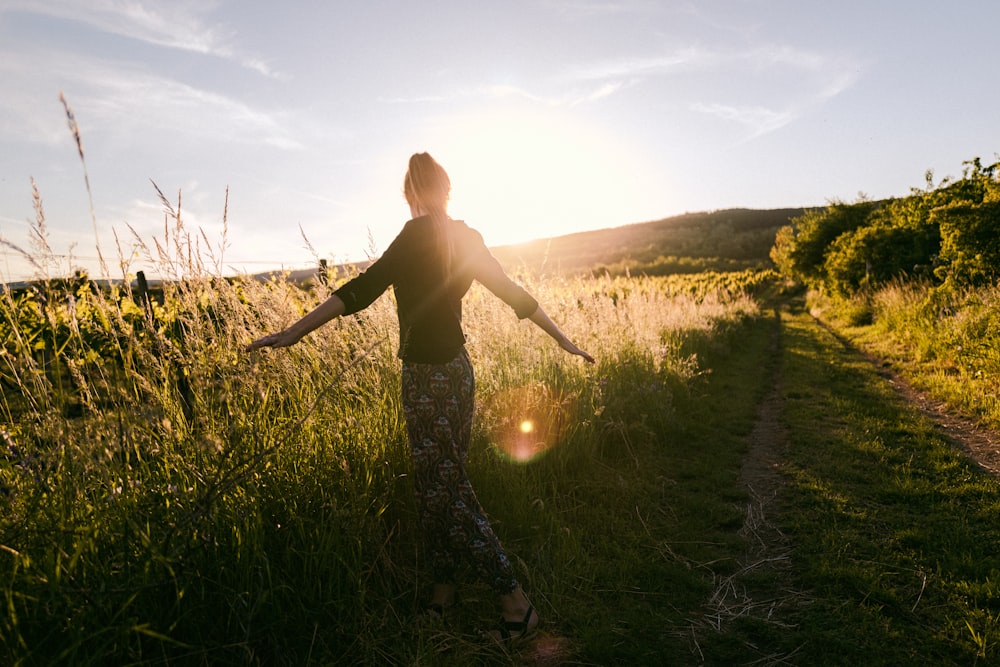 a woman standing in a field with her arms outstretched