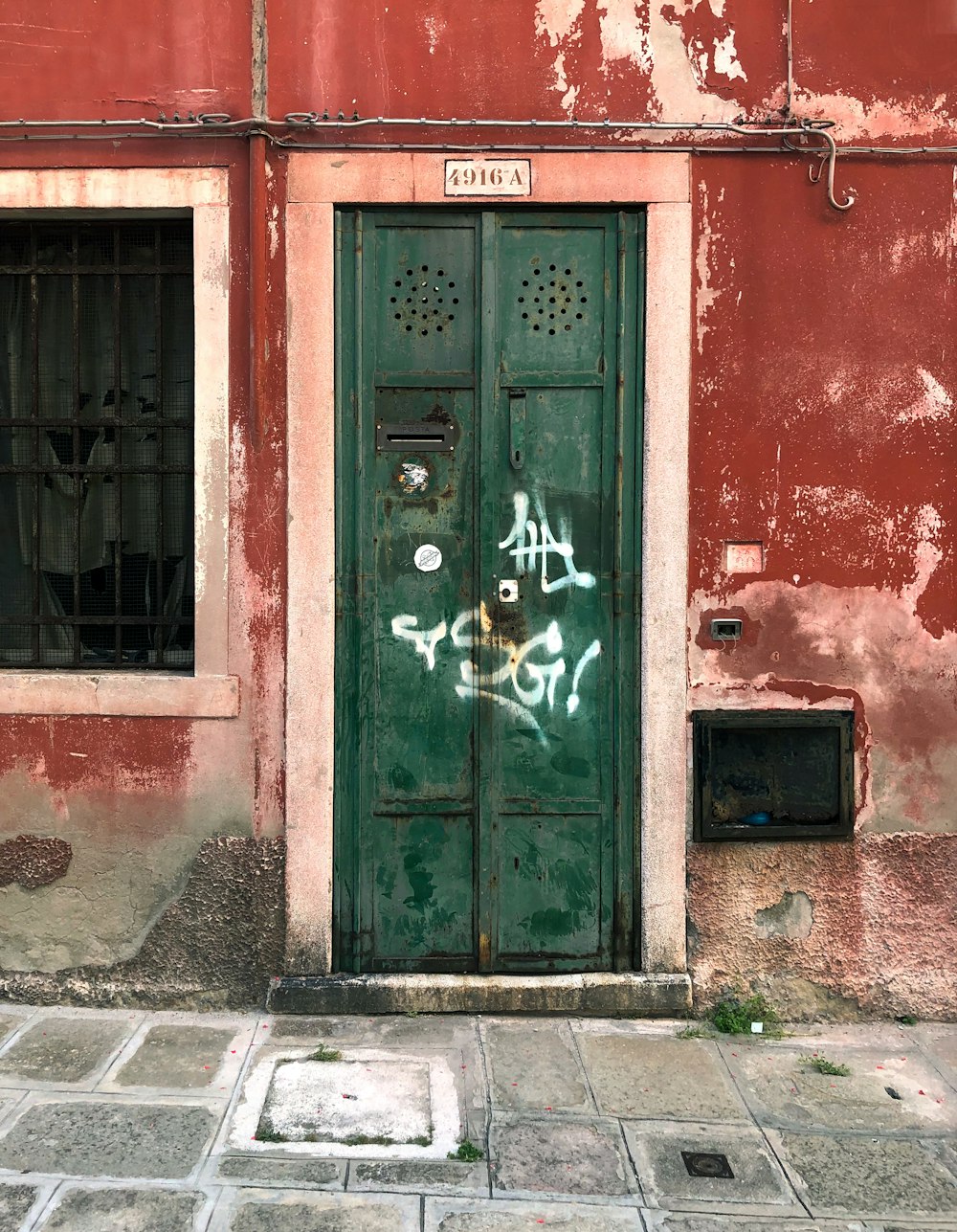 a green door with graffiti on the side of a building