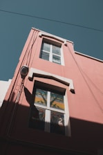 a red building with a window and a bird painted on it